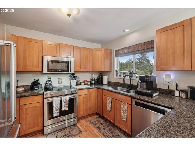 a kitchen with stainless steel appliances granite countertop a stove sink microwave and window