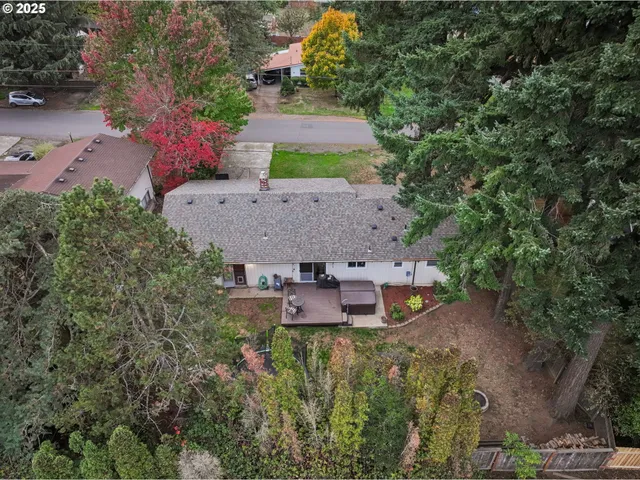 an aerial view of residential house with outdoor space and trees all around