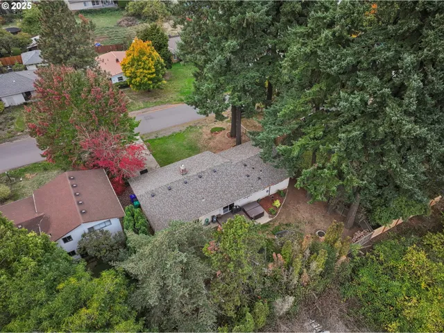 an aerial view of residential house with outdoor space and trees all around