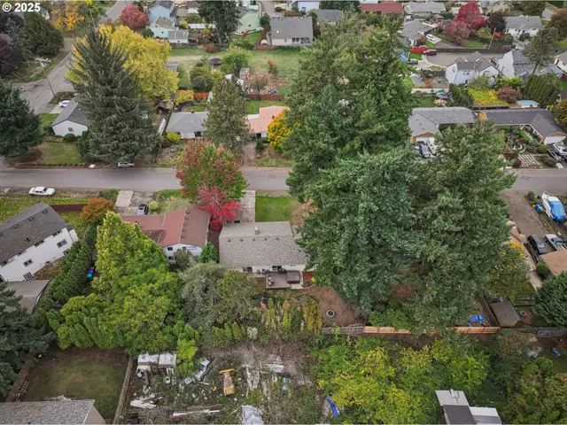 an aerial view of residential houses with outdoor space and trees