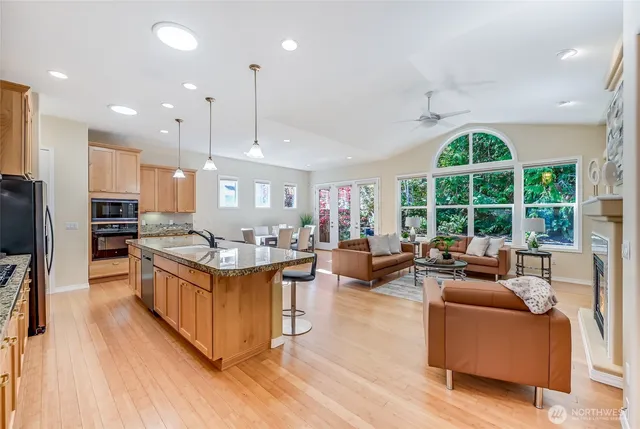 a kitchen with stainless steel appliances granite countertop a stove and a view of living room