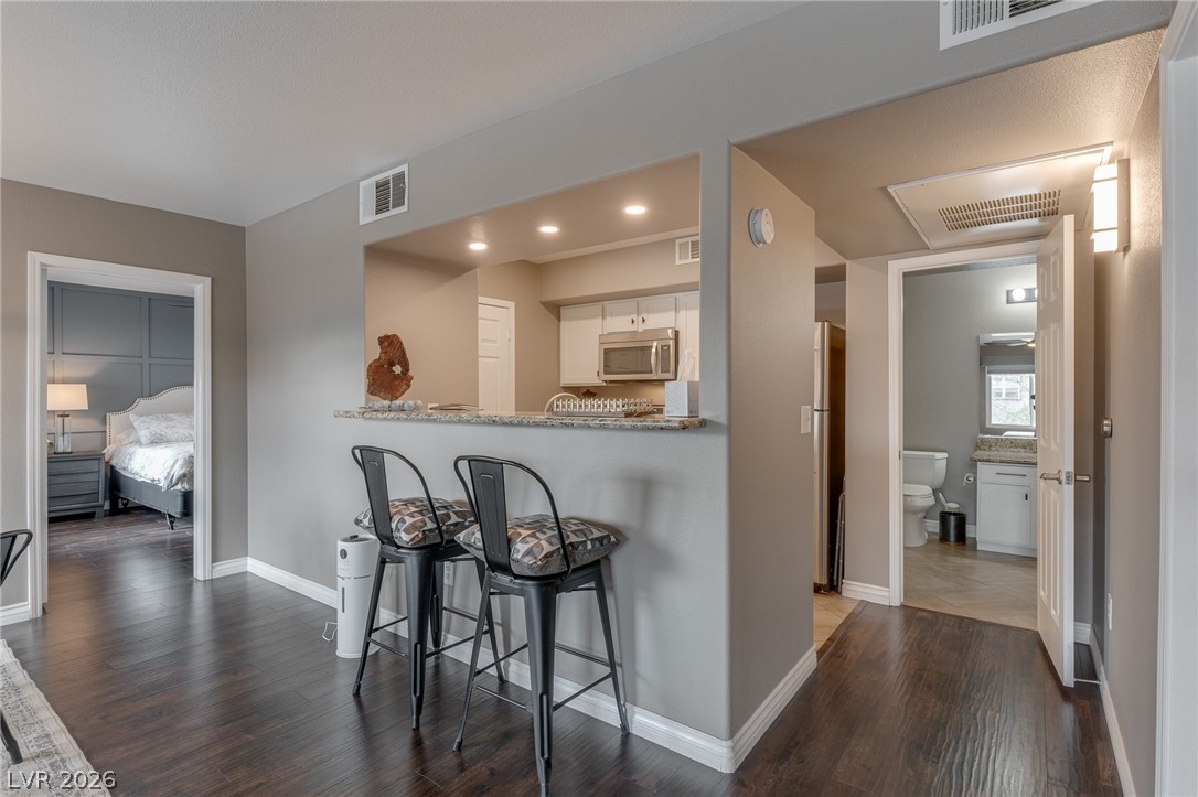 7255 West Sunset Road, Unit 2155 Las Vegas, NV 89113 - Photo 10 of 21 Kitchen with a kitchen breakfast bar, dark wood finished floors, appliances with stainless steel finishes, white cabinets, and recessed lighting