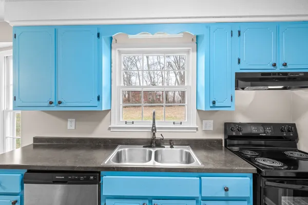 a kitchen with a sink a stove cabinets and a window