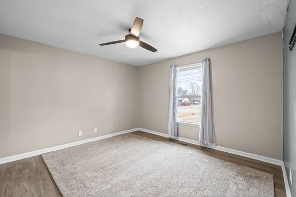 an empty room with a ceiling fan and window