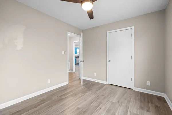 an empty room with wooden floor chandelier fan and windows