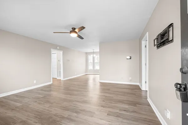 a view of an empty room with window and wooden floor