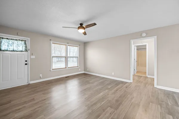 a view of an empty room with wooden floor and a window