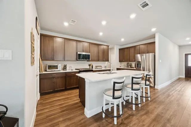 a kitchen with a sink a counter top space stainless steel appliances and cabinets