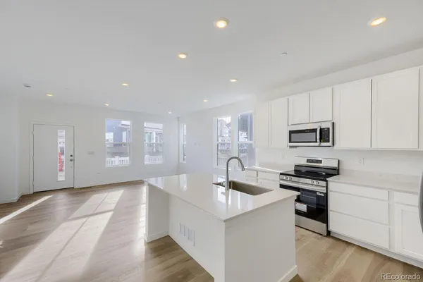 a kitchen with stainless steel appliances granite countertop a sink and white cabinets