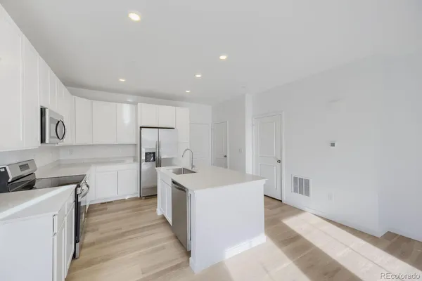 a large kitchen with a lot of counter space and wooden floor