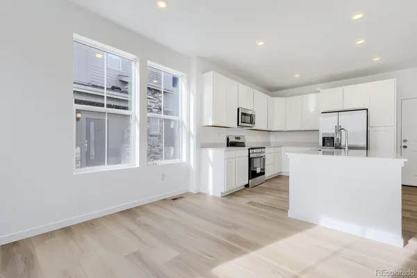 a kitchen with white cabinets and appliances
