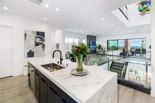 a kitchen with stainless steel appliances granite countertop a sink a stove and a dining table with wooden floor