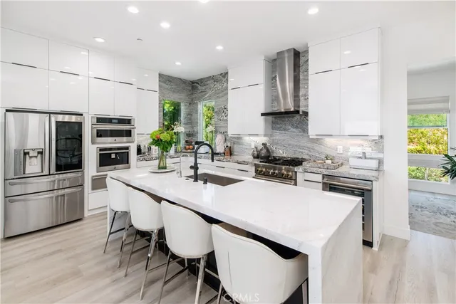 a kitchen with stainless steel appliances a stove a sink a microwave a refrigerator and chairs