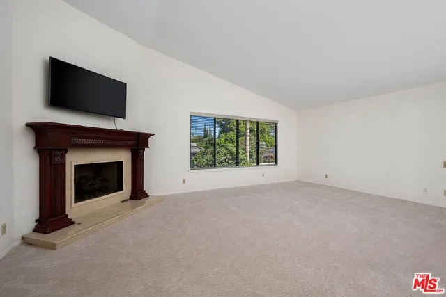 a view of an empty room with a fireplace and a flat screen tv