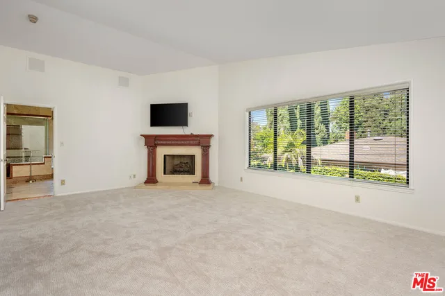 a view of an empty room with a fireplace and a window
