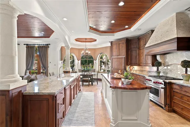 a kitchen with stainless steel appliances granite countertop a stove top oven a sink a dining table and chairs with wooden floor