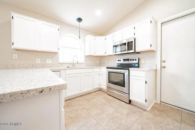 a kitchen with stainless steel appliances granite countertop white cabinets a sink a stove a refrigerator and white cabinets