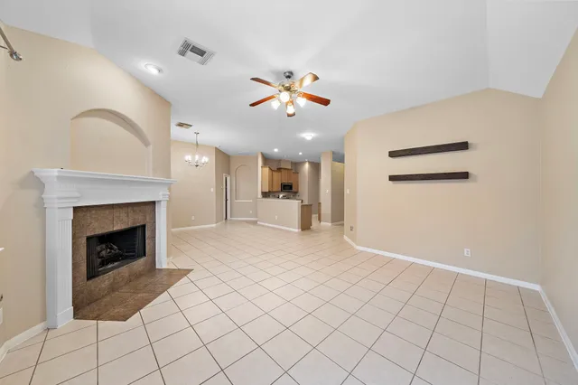 a view of an empty room with kitchen and fireplace