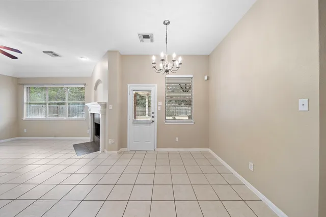a view of an empty room with window and chandelier
