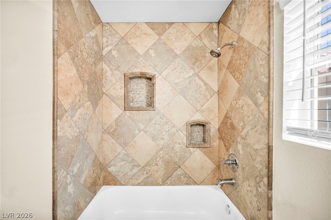 6405 North Raptor Court North Las Vegas, NV 89084 - Photo 29 of 66 Ornate tilework and built-in niches elevate this inviting bathtub and shower combination.
