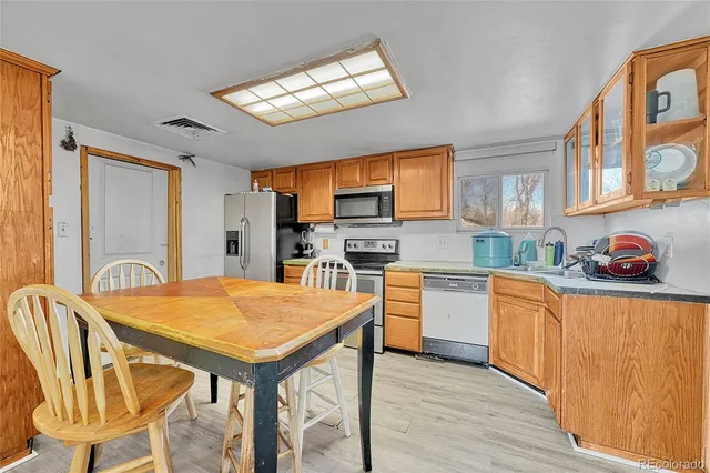 a kitchen with stainless steel appliances granite countertop a stove a sink dishwasher and a refrigerator with wooden floor