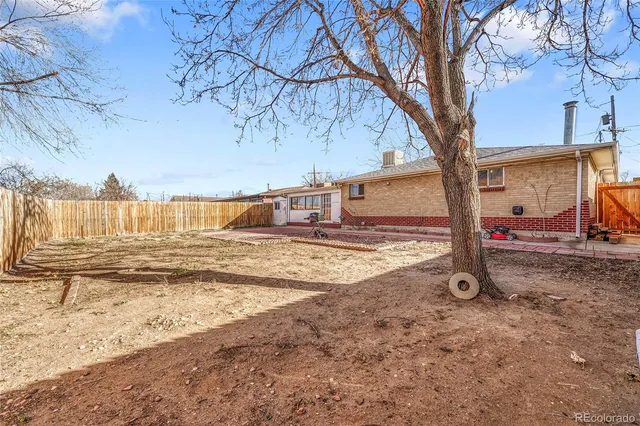 a view of a backyard with wooden fence and a large tree