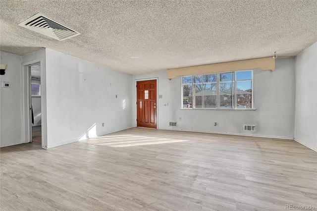 a view of an empty room with a window and wooden floor