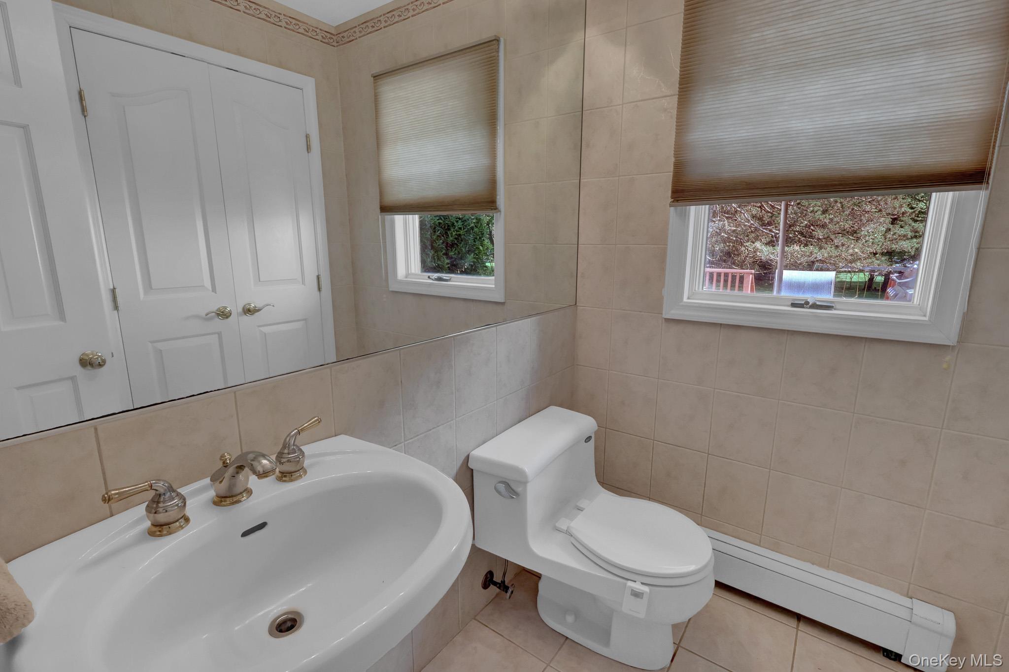 15 Stillwater Road Nissequogue, NY 11780 - Photo 22 of 43 Pedestal sink with brass-finish faucet, full vanity mirror, and neutral-toned wall tile