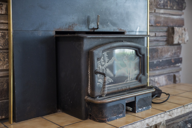 634 South 2100th Street West Vernal, UT 84078 - Photo 23 of 71 Black cast iron wood-burning stove with an etched glass door, set on a tiled hearth