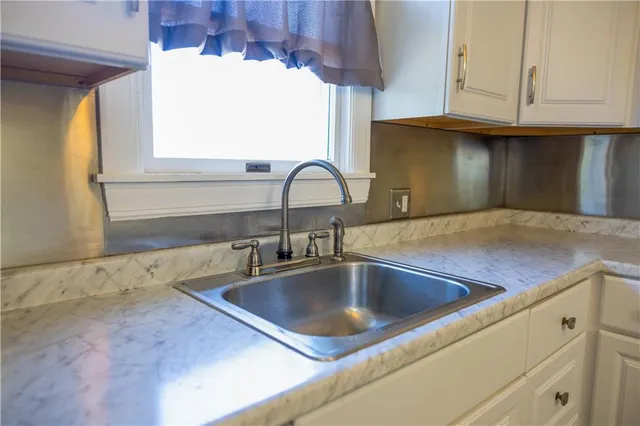 a kitchen with stainless steel appliances granite countertop a refrigerator a stove a sink and white cabinets