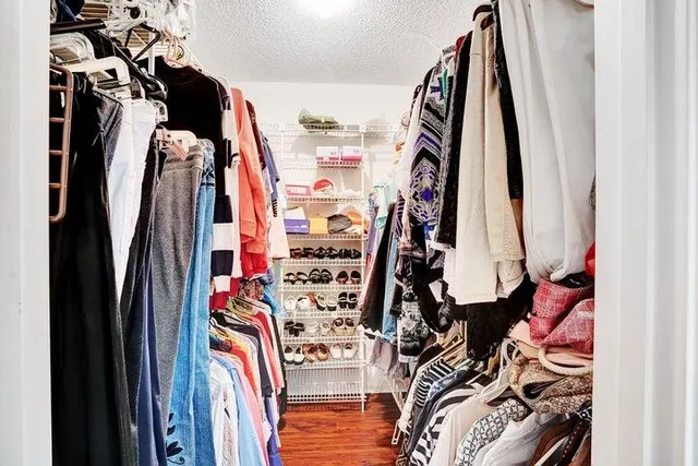 a view of walk in closet with clothes and shoes