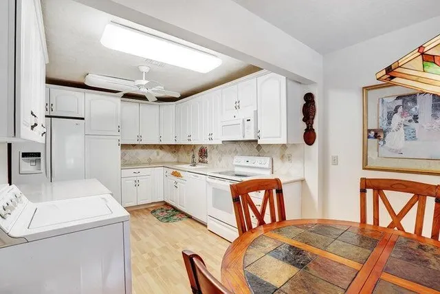 a open kitchen with stainless steel appliances granite countertop a stove a sink dishwasher and white cabinets with wooden floor