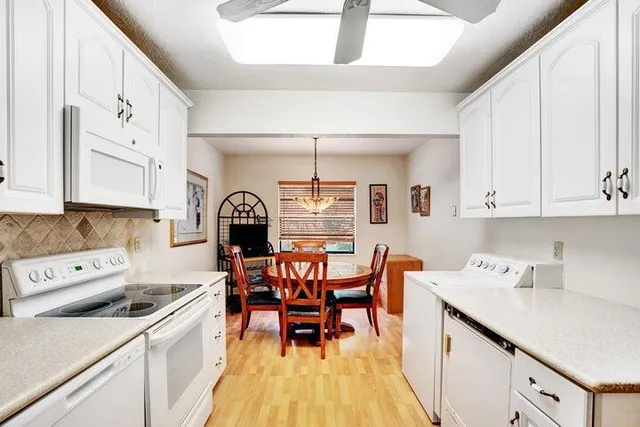 a kitchen with a dining table chairs and white appliances