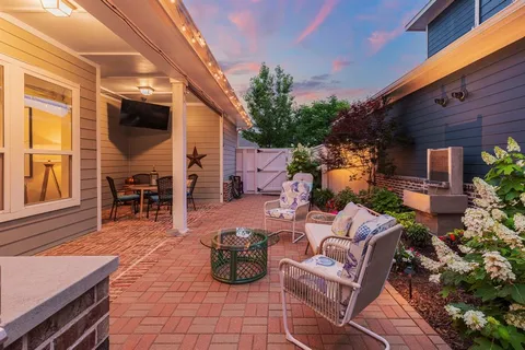 a view of a backyard with table and chairs potted plants fire pit and wooden fence