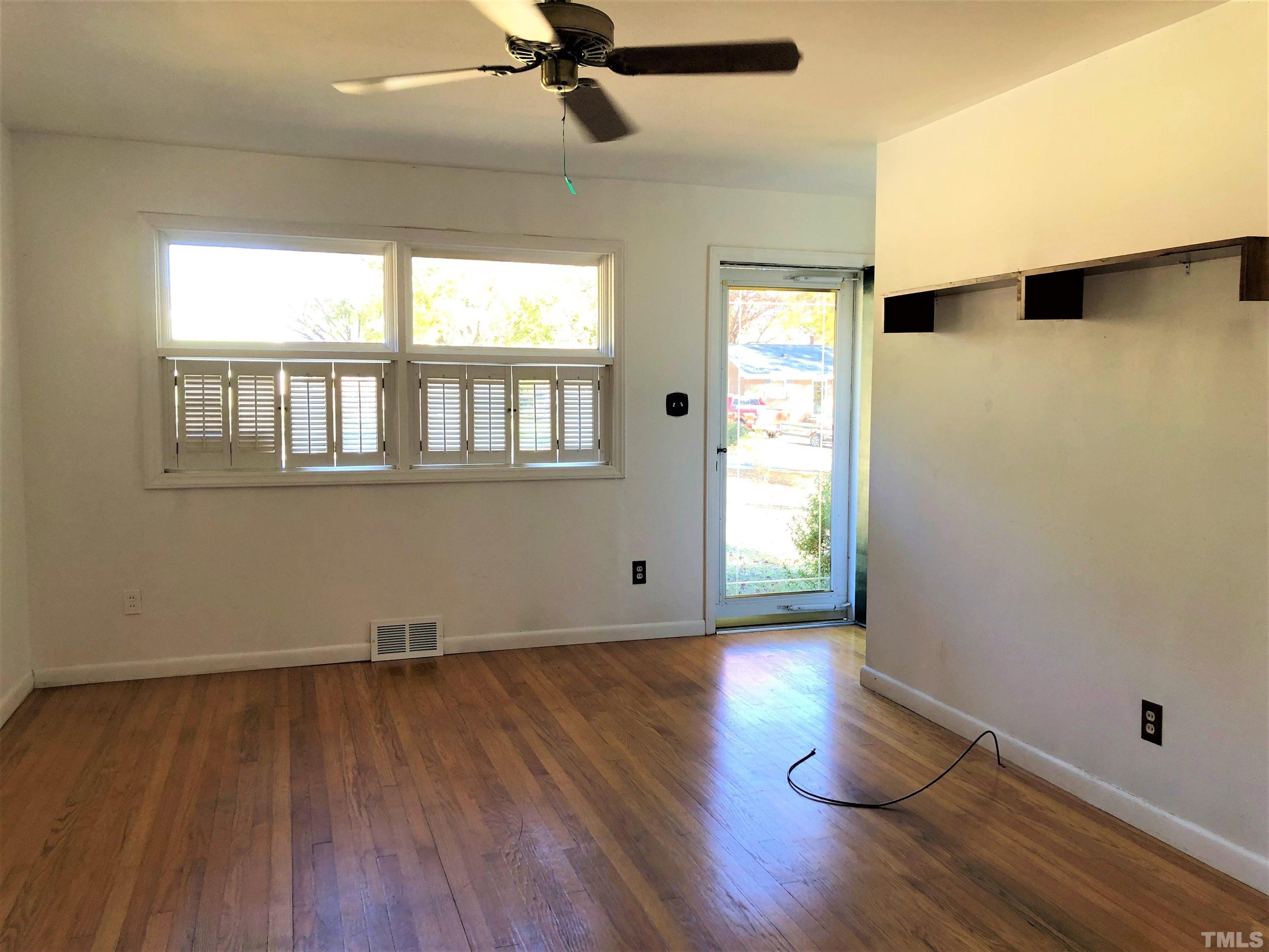 1402 Southerlund Road Garner, NC 27529 - Photo 2 of 18 an empty room with wooden floor fan and windows