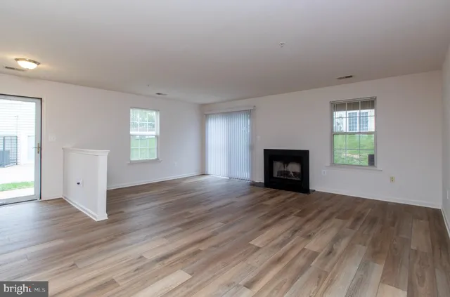 an empty room with wooden floor and fireplace