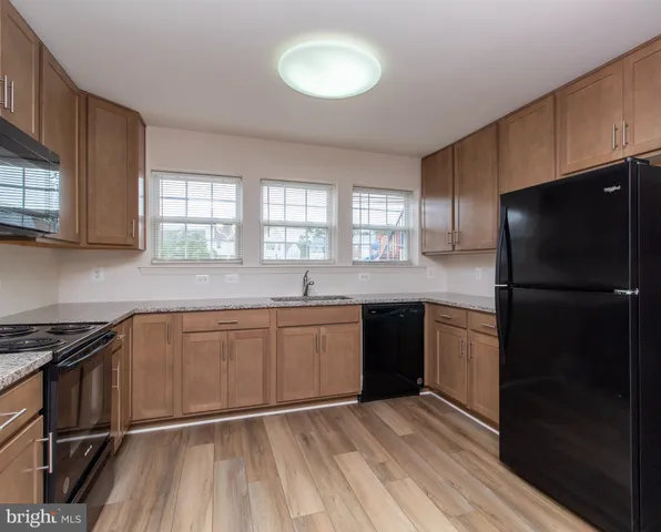 a kitchen with granite countertop a refrigerator stove top oven and sink