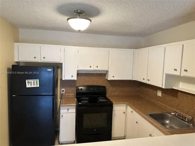 a kitchen with white cabinets and black appliances