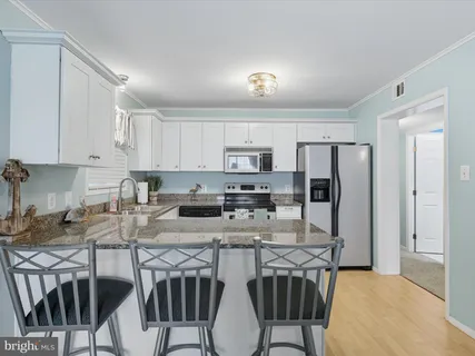 a kitchen with stainless steel appliances granite countertop a table chairs microwave and refrigerator