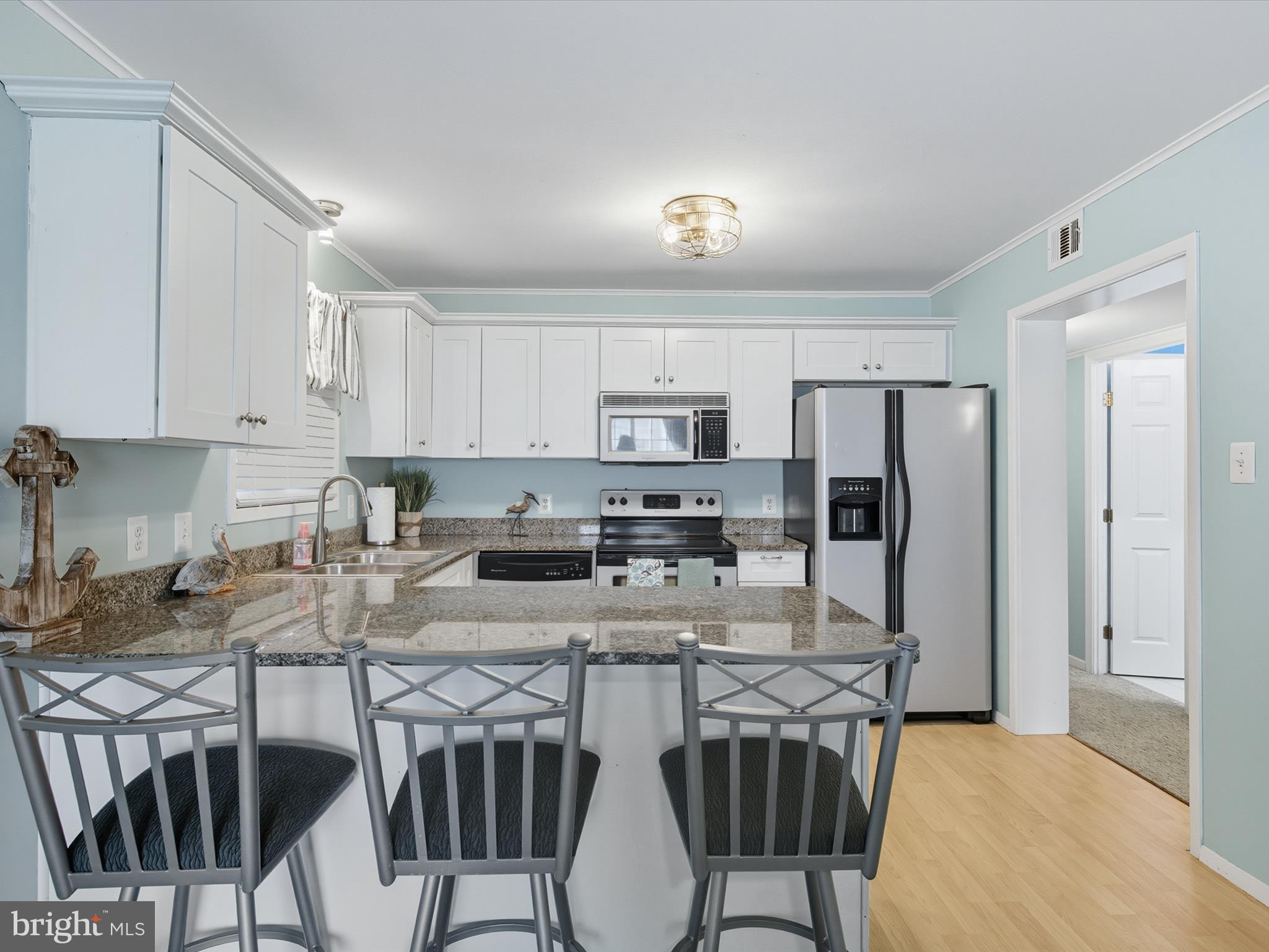 710 Bradley Road, Unit A2 Ocean City, MD 21842 - Photo 7 of 40 a kitchen with stainless steel appliances granite countertop a table chairs microwave and refrigerator