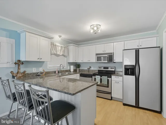 a kitchen with stainless steel appliances granite countertop a stove a refrigerator a sink a dining table and chairs