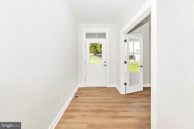 a view of a hallway with wooden floor and a bathroom