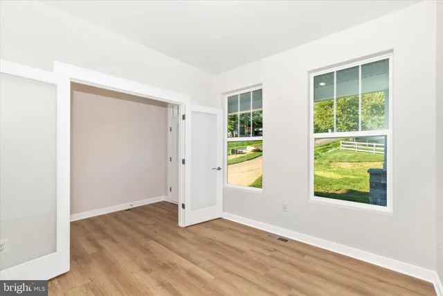 an empty room with wooden floor and windows