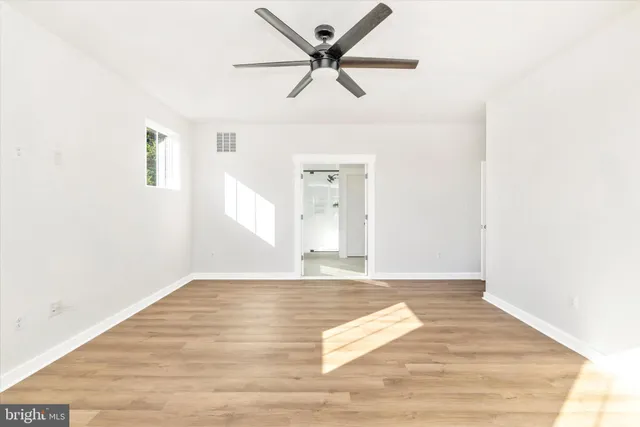a view of empty room with wooden floor and ceiling fan