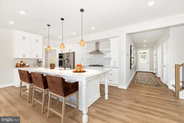a kitchen with stainless steel appliances kitchen island granite countertop a table chairs and a wooden floor
