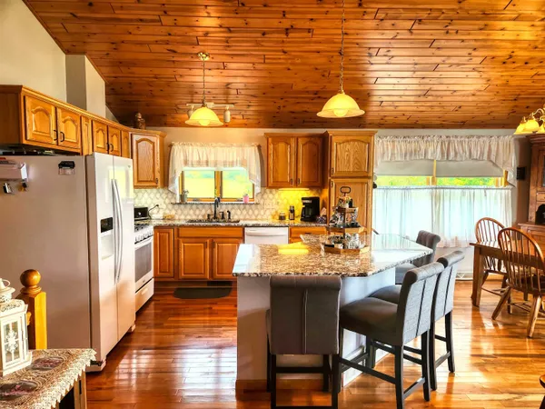 an open kitchen with granite countertop a stove and a flat screen tv