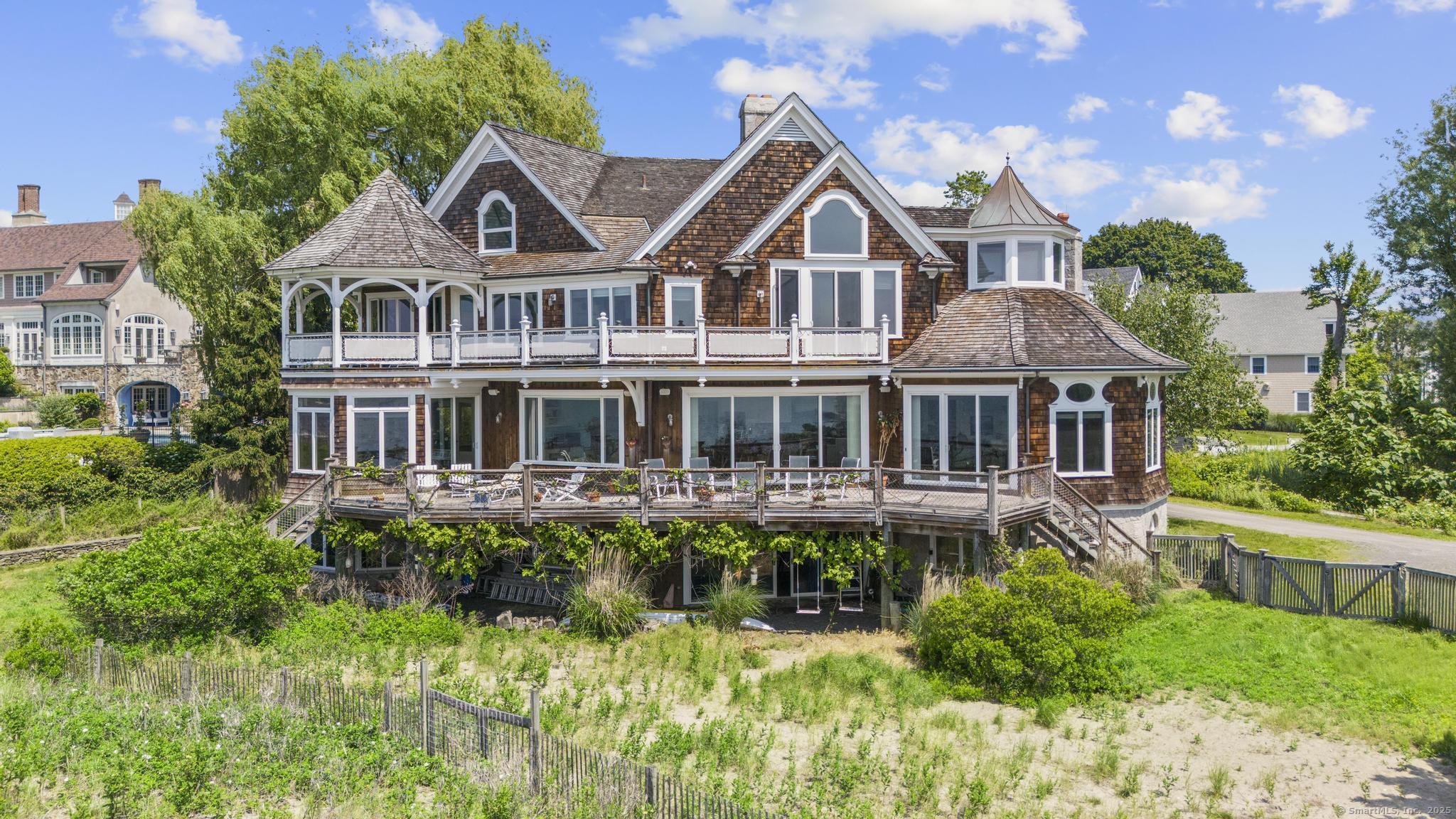 1410 South Pine Creek Road Fairfield, CT 06824 - Photo 14 of 40 a front view of a house with a yard table and chairs