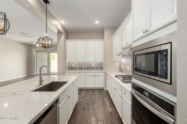 an empty room with wooden floor chandelier fan and windows