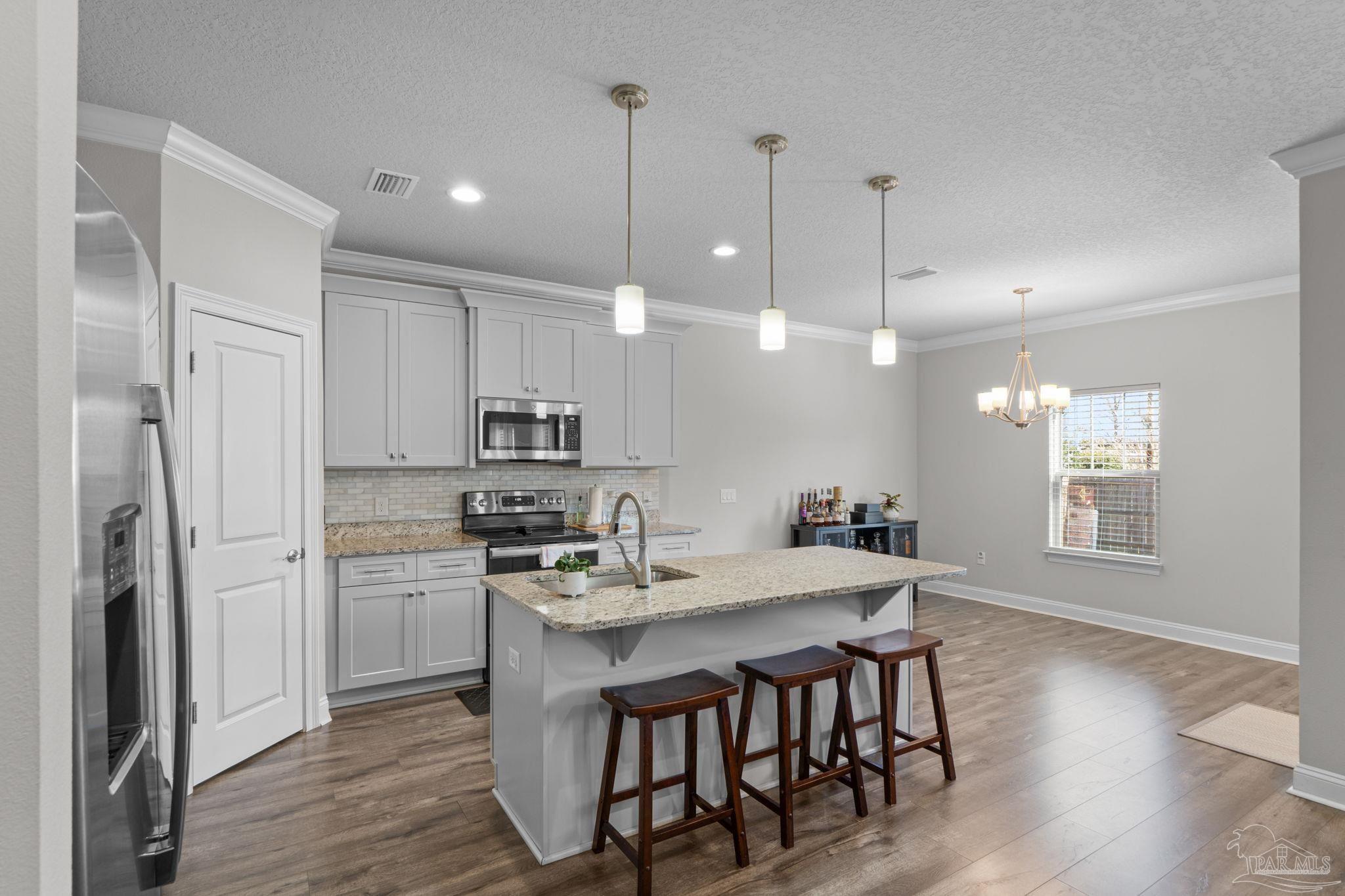 2770 Joe Pruitt Road Navarre, FL 32566 - Photo 12 of 58 a kitchen with stainless steel appliances kitchen island granite countertop a sink a stove a refrigerator and island with wooden floor