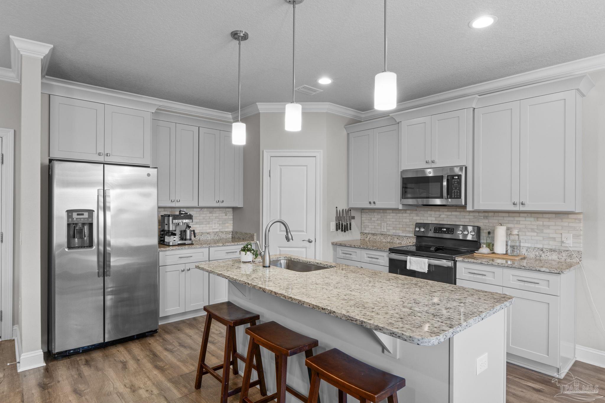 2770 Joe Pruitt Road Navarre, FL 32566 - Photo 13 of 58 a kitchen with stainless steel appliances granite countertop a sink a stove a refrigerator cabinets and chairs